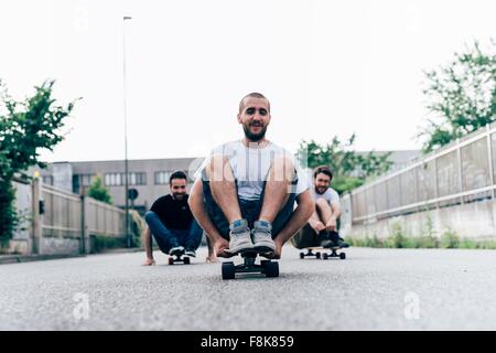 Three young men sitting on skateboards Stock Photo