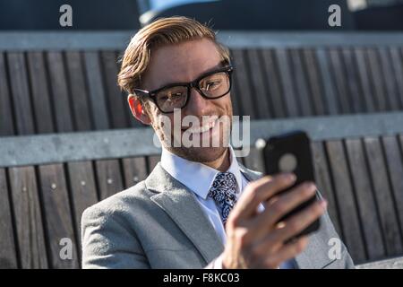 Young businessman reading smartphone text in city Stock Photo