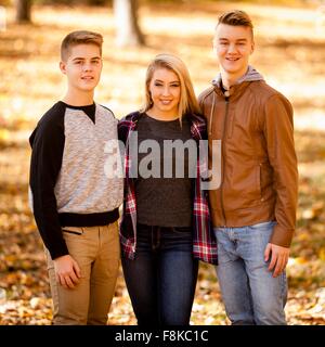 Portrait of young woman and two teenage brothers in autumn forest Stock Photo