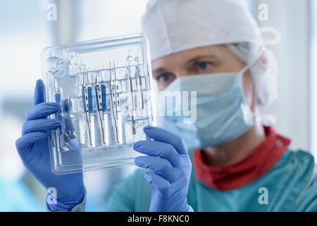 Worker inspecting surgical instruments in clean room of surgical instruments factory, close up Stock Photo