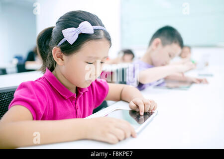 Girl sitting with boy using digital tablet in classroom Stock Photo