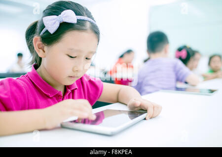 Girl sitting with boy using digital tablet in classroom Stock Photo