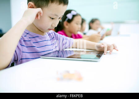 Boy sitting with girl using digital tablet in classroom Stock Photo