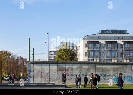 Remains of the Berlin wall with Grafitti, and tourists visiting Stock Photo
