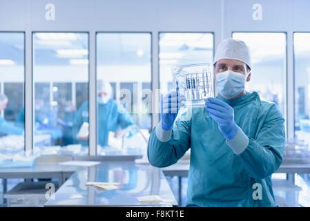 Worker inspecting surgical instruments in clean room of surgical instruments factory Stock Photo