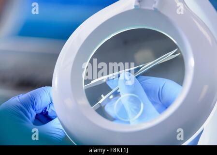 Worker inspecting surgical instruments in clean room of surgical instruments factory, close up Stock Photo