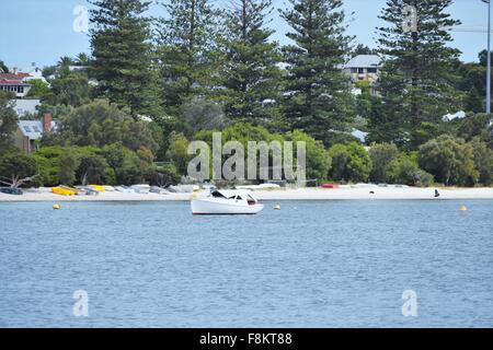scenic shot of a moored boat and smaller boats upside down, lined up on the banks of the swan river Stock Photo