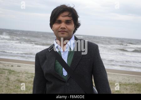 A businessman on the beach near sea with strong wind Stock Photo