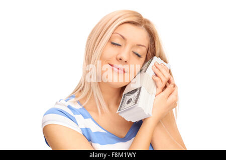 Young blond woman sleeping with a stack of dollar bills against her cheek and smiling isolated on white background Stock Photo