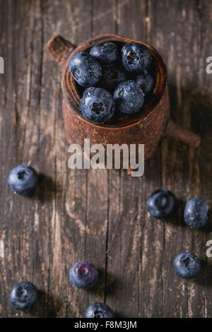 Close up of fresh wet blueberries in decorative stump over old wooden table. Top view Stock Photo