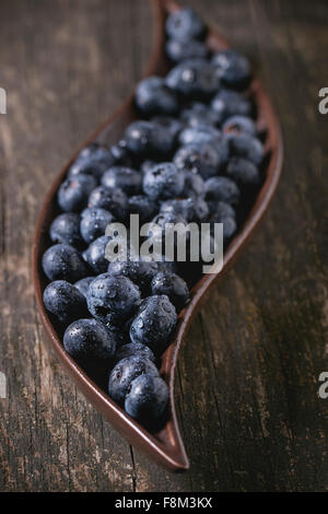 Close up of fresh wet blueberries in decorative ceramic plate over old wooden table Stock Photo