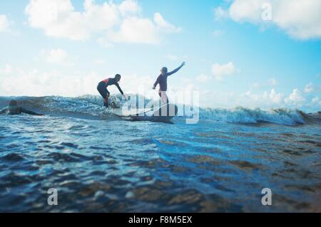 Two surfers surfing in sea Stock Photo