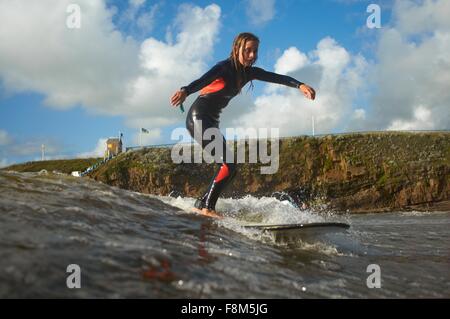 Young female surfer riding wave Stock Photo