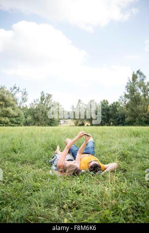 Young couple lying on grass in field, taking self portrait using smartphone