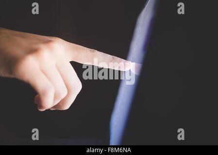 Side view of hand pointing at computer screen Stock Photo