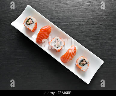 Sushi and rolls on a rectangular white plate and slate table Stock Photo