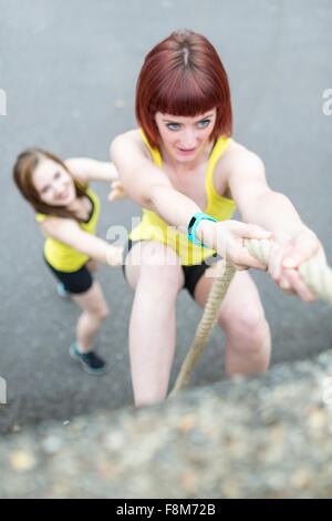 Young women climbing over wall with rope Stock Photo