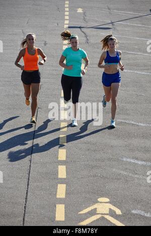 Three young female runners running in parking lot Stock Photo