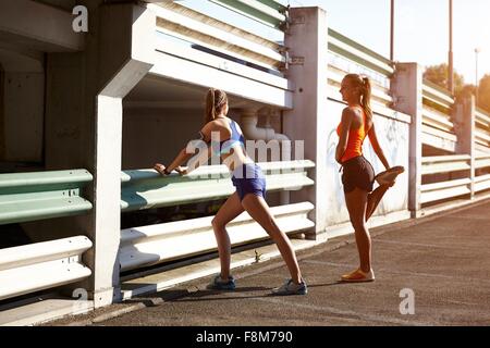 Two young female runners warming up in parking lot Stock Photo