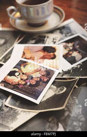 Pile of family photographs on table, next to tea cup Stock Photo