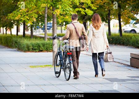 Casual businessman and woman pushing bike Stock Photo