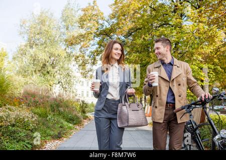 Casual businessman and woman pushing bike with coffee Stock Photo