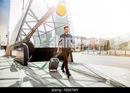 Businessman with wheeled suitcase by escalator Stock Photo