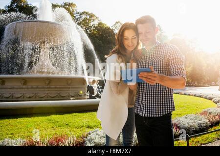 Couple using digital tablet in park Stock Photo