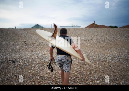 Surfer carrying surfboard on beach Stock Photo