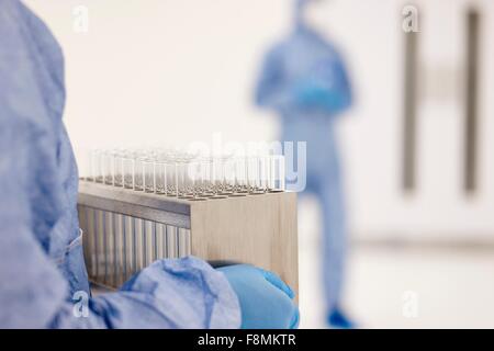 Scientist carrying tray of test tubes in laboratory Stock Photo