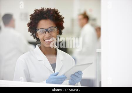 Scientist smiling in laboratory, colleagues working in background Stock Photo