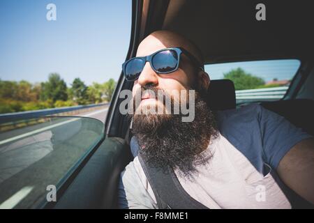 Bearded man looking out of car window on highway, Garda, Italy Stock Photo