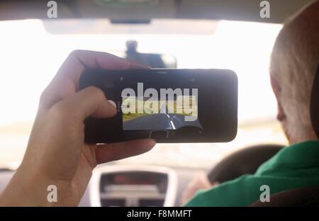 Womans hand in car photographing diminishing perspective of rural road, Cumbria, UK Stock Photo