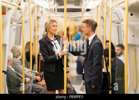 Businessman and businesswoman talking in tube, London Underground, UK Stock Photo