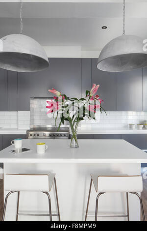 Island unit in kitchen with bar stools and industrial lights. Lights off Stock Photo