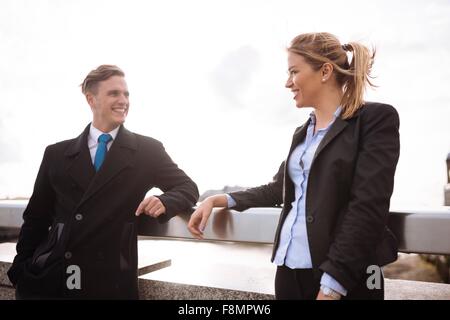 Businessman and businesswoman leaning on rail Stock Photo