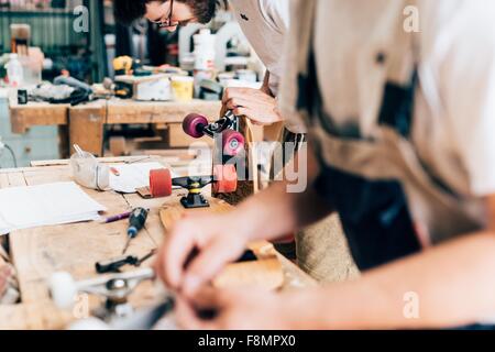 Young men in carpentry workshop looking down making skateboards Stock Photo