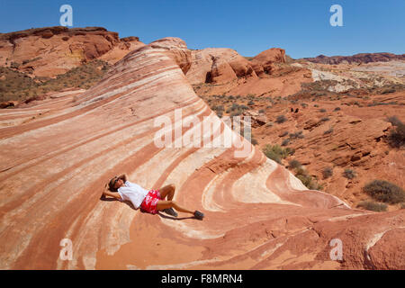 girl, lying in the desert wave of Valley of Fire, Nevada Stock Photo