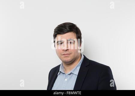 Dark-haired european businessman with a funny look stares into the camera while in front of a gradient background Stock Photo