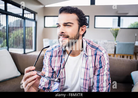 Smiling man holding glasses looking away Stock Photo
