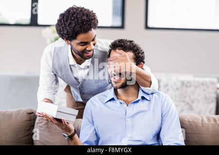 Handsome man covering boyfriends eyes and giving a gift Stock Photo