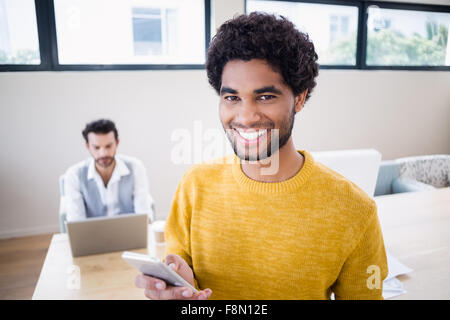 Smiling man using smartphone with partner in background Stock Photo