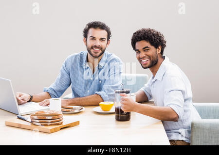 Happy gay couple having breakfast and using laptop Stock Photo