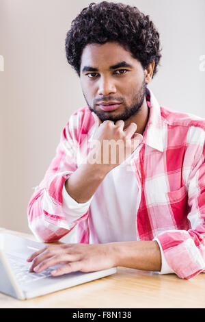 Thoughtful man using laptop looking at the camera Stock Photo