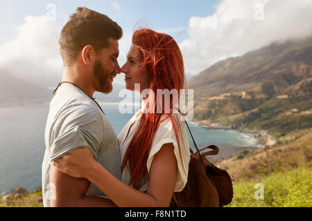 Portrait of young man and woman standing face to face. Affectionate young couple enjoying their love in nature outdoors. Stock Photo