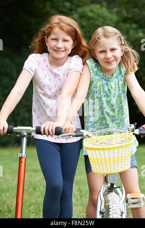 Two Girls Playing On Bike And Scooter Outdoors Stock Photo