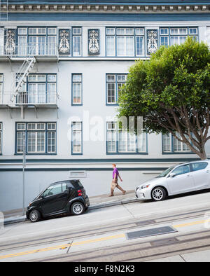 A man walks down a steep incline on California Street, in the heart of San Francisco, California. Stock Photo
