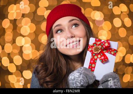 Inspired lovely girl in red hat and knitted mittens holding blank cards with red ribbon over glittering background Stock Photo