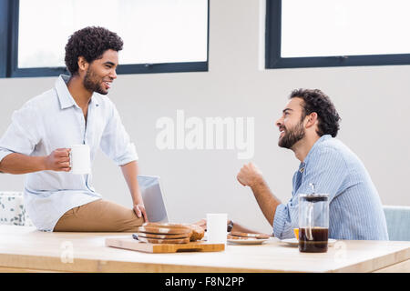 Happy gay couple using laptop and talking Stock Photo