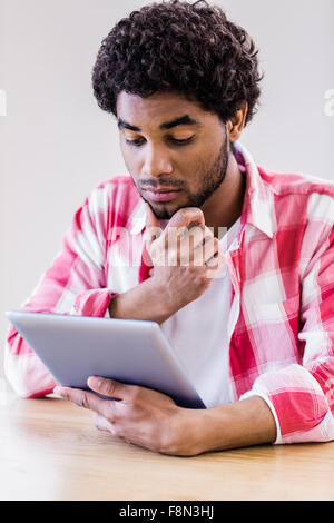 Thoughtful man using tablet Stock Photo